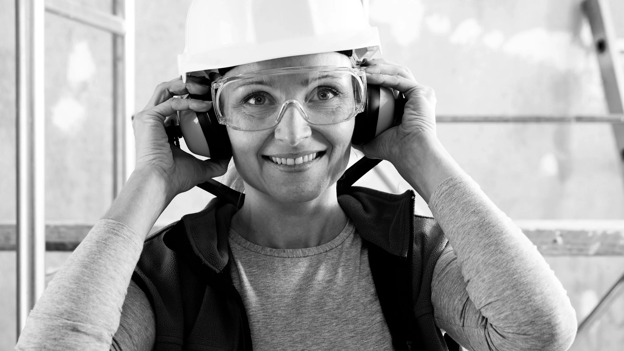 Black-and-white portrait of a construction worker with protective ear gear on.