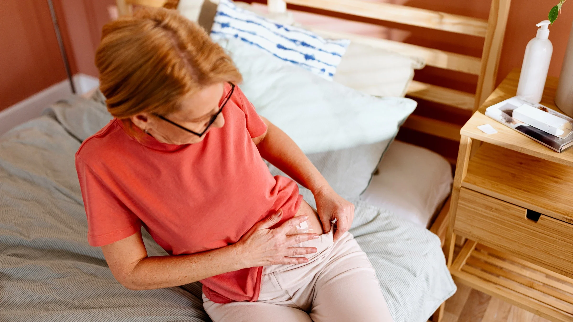A person sticking a HRT patch on their stomach to treat menopause symptoms.