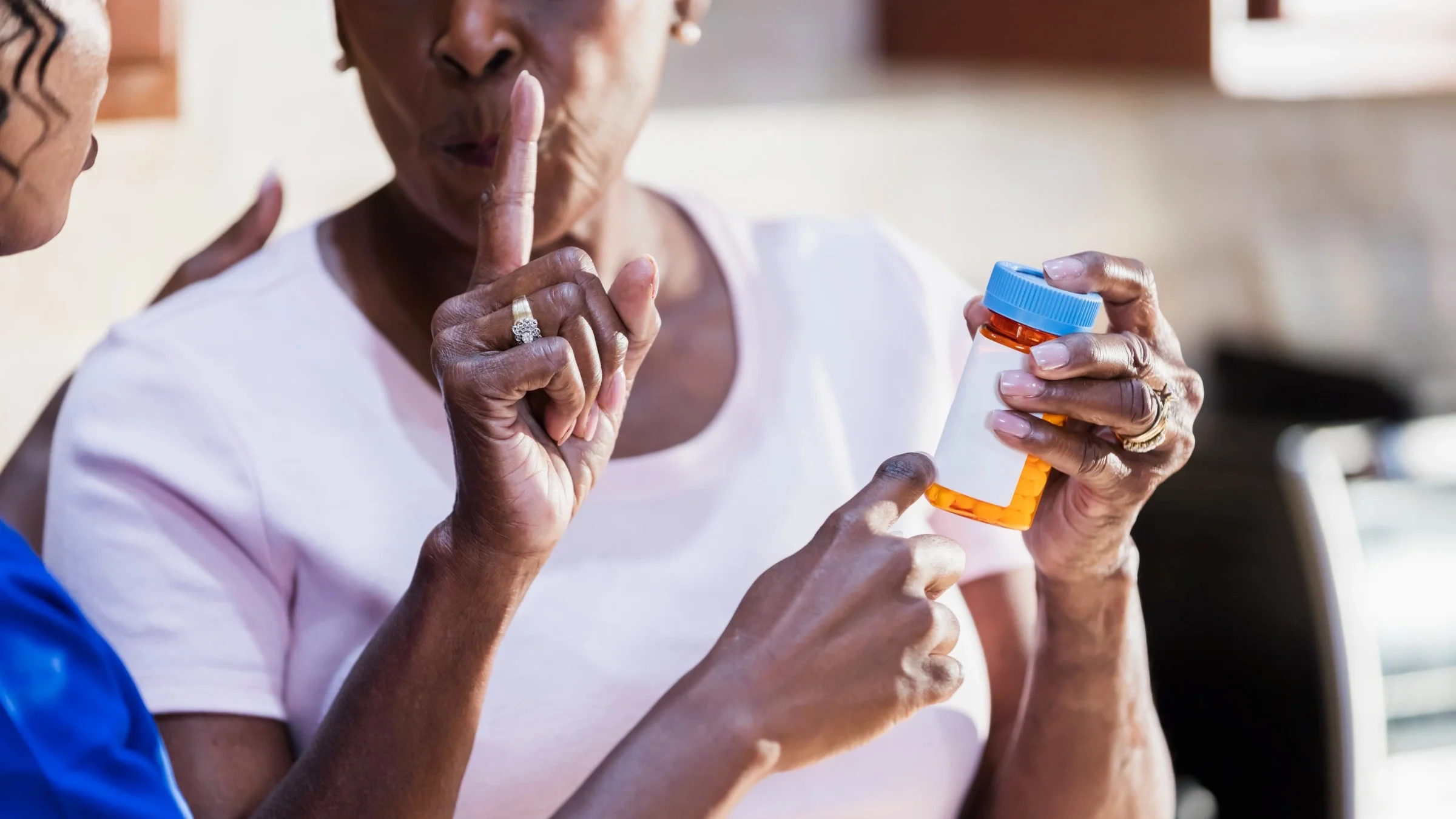 A patient talking to a nurse and reviewing the prescription bottle in her hand.