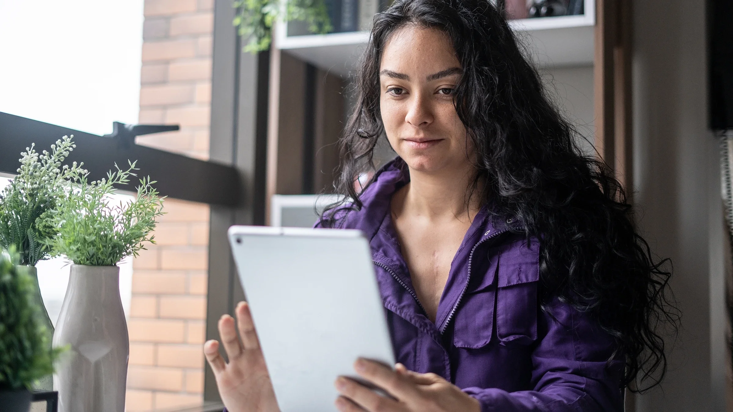 A woman is using a tablet at home.