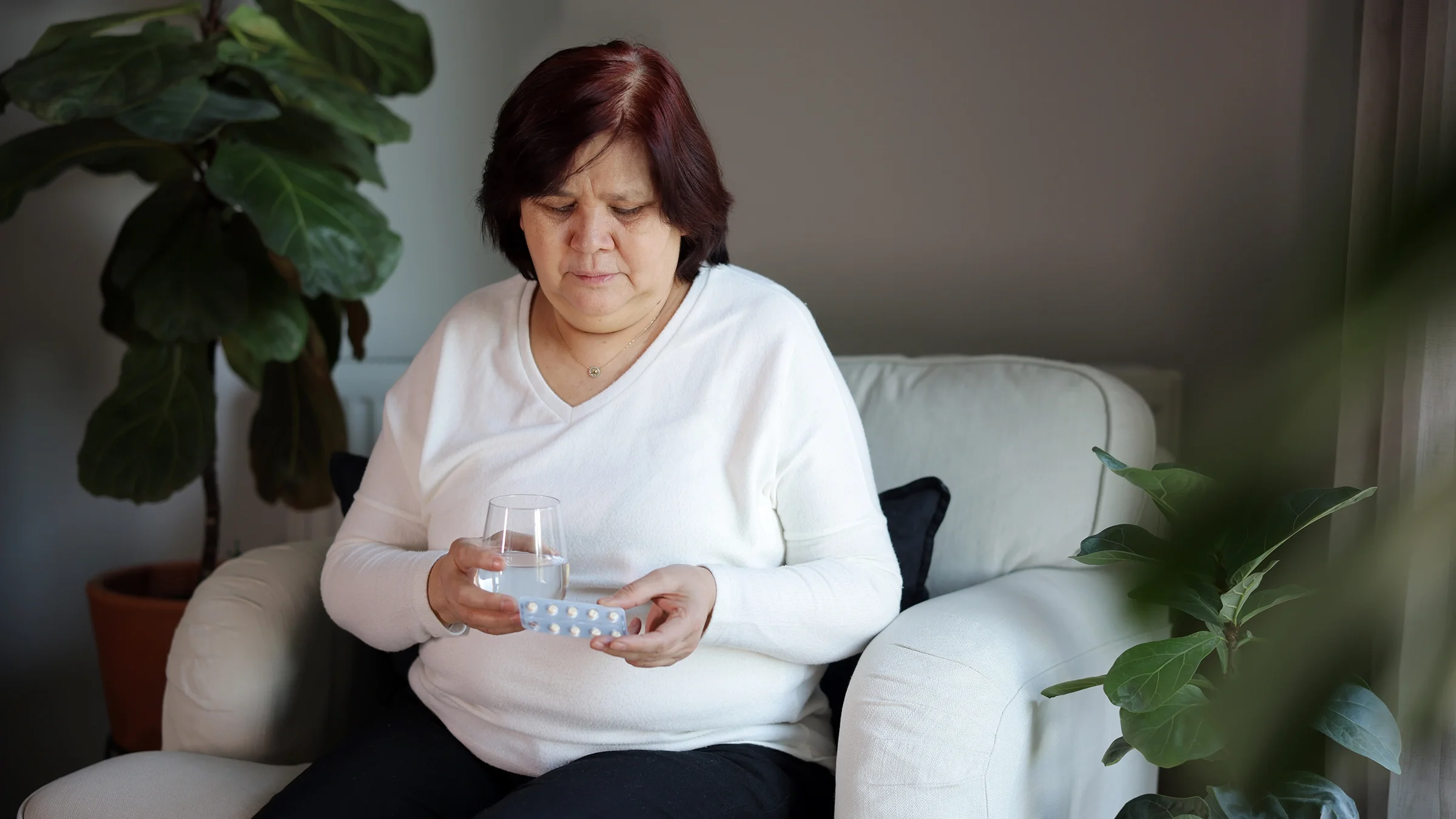 Woman taking her daily medication with a glass of water.