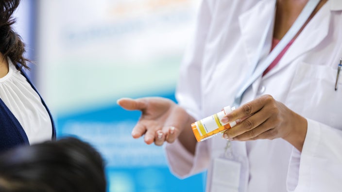 A pharmacist discusses a medication with a customer.