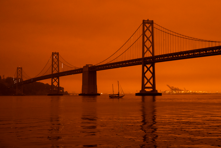 The SF Bay Bridge surrounded by smoke and in a dark orange and red haze during the Northern California wildfires.