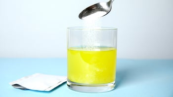 Miralax: disolveable medication packet powder pouring into glass yellow liquid-1311404738