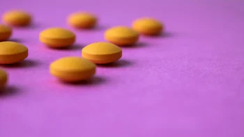 Health: statins: orange round pills on purple background-1073377856