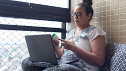 A person holding a pill bottle and on a telehealth call.
wagnerokasaki/E+ via Getty Images 