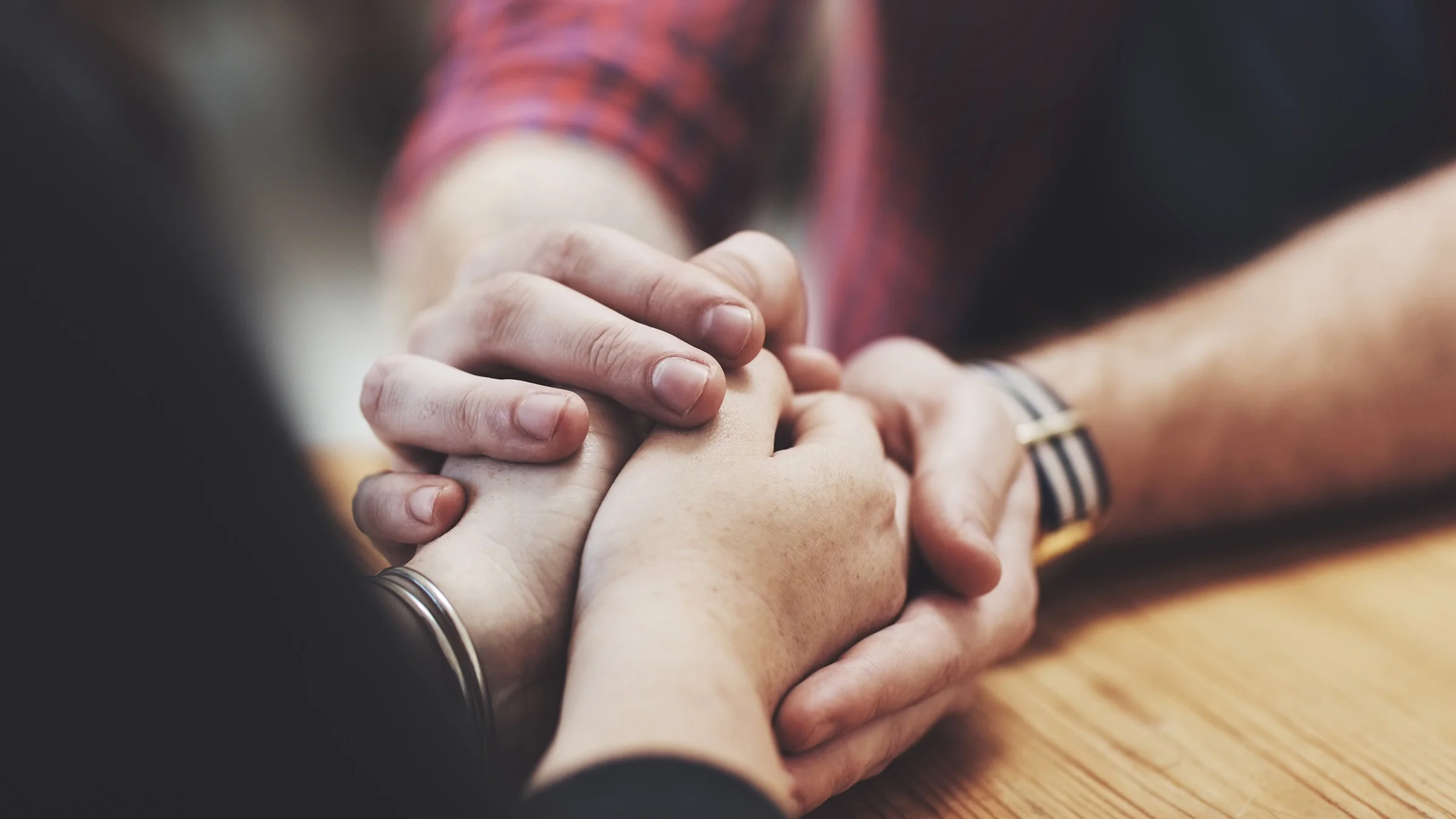 Close-up on two people holding hands across the table.