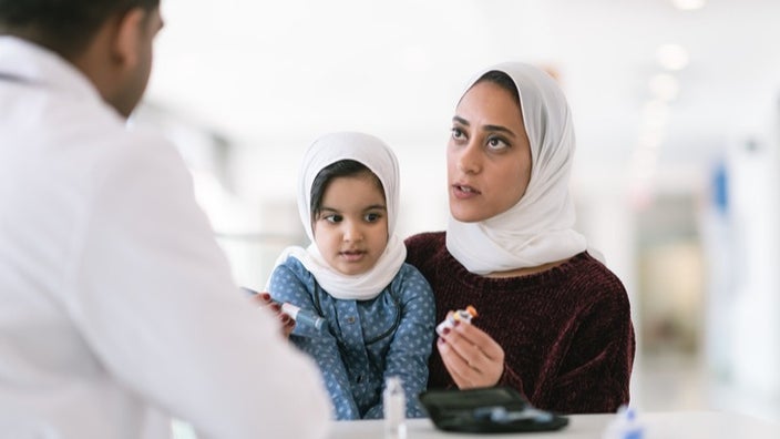 Mother with her young daughter talking with the doctor about diabetes medications.