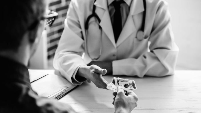 Black and white cropped shot of a patient paying a doctor in a white coat.