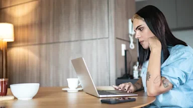 Trans woman researching information on her laptop at the dining table.
FG Trade/E+ via Getty Images
