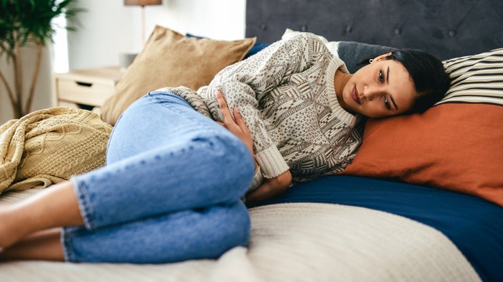 A person experiencing stomach pain in bed.