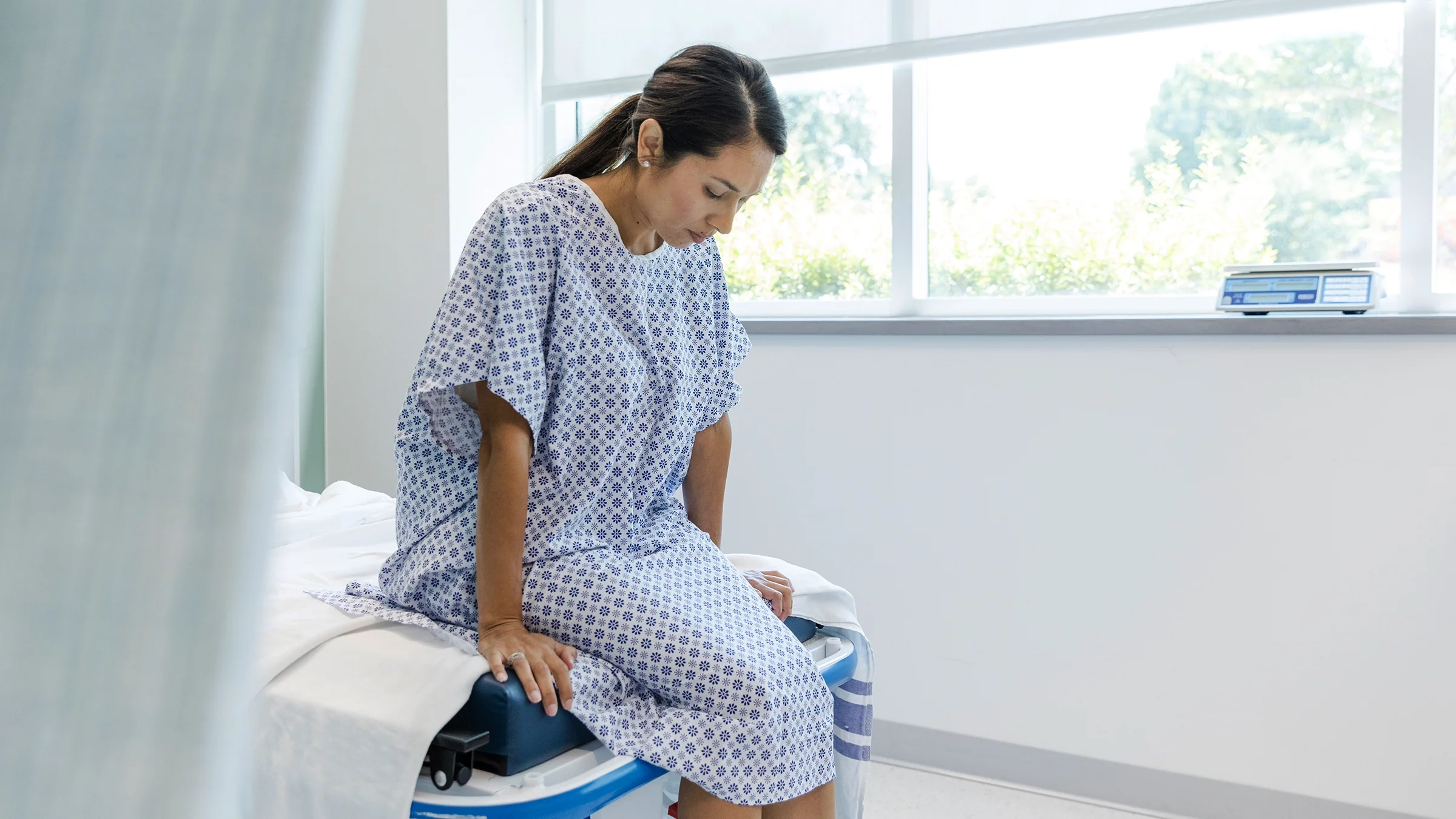 Woman in hospital gown waits for test results.