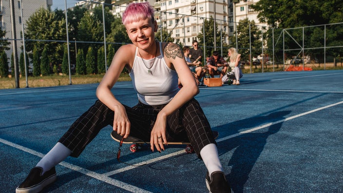 Someone chilling on a skateboard at a sports court.
