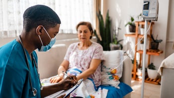 Lung cancer: woman hooked up to IV nurse reporting on clipboard 1348098836