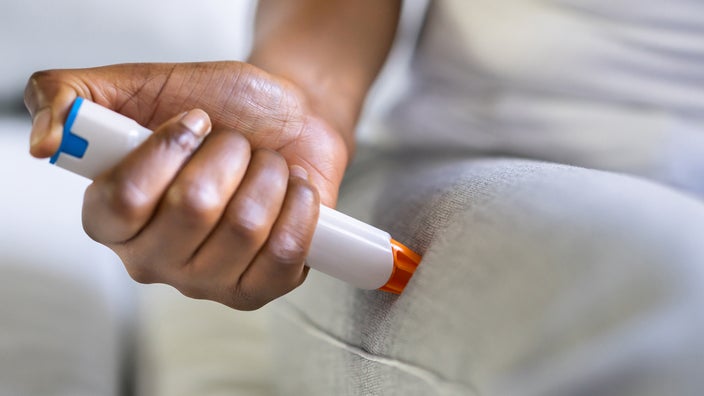 A close-up of an EpiPen injection in a thigh.
