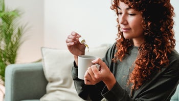 Cannabinoids: woman adding CBD oil to tea-1364649183
