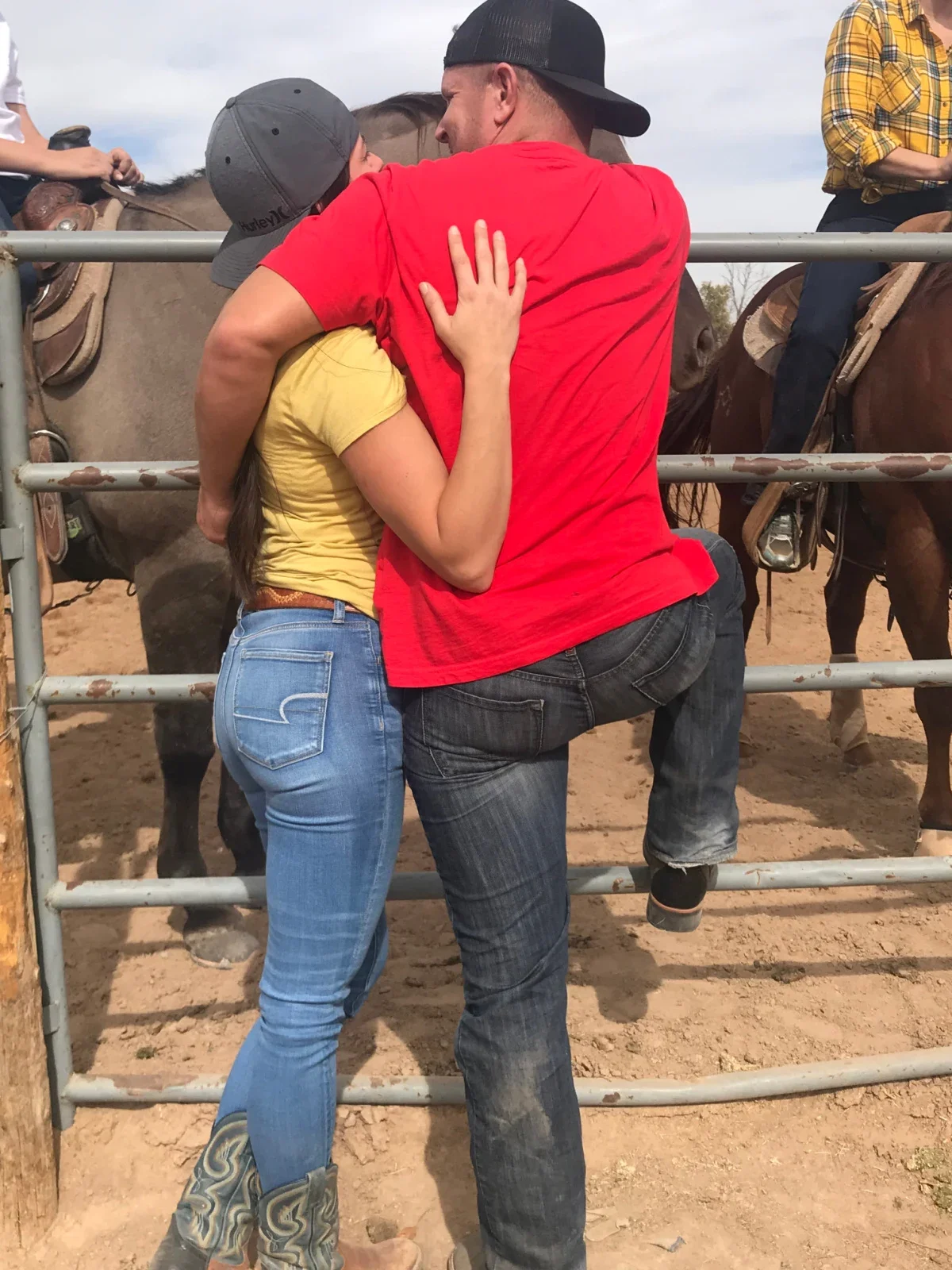 Lindsay and Rhead Kelly are pictured from behind, leaning on a gate near a horse pen.