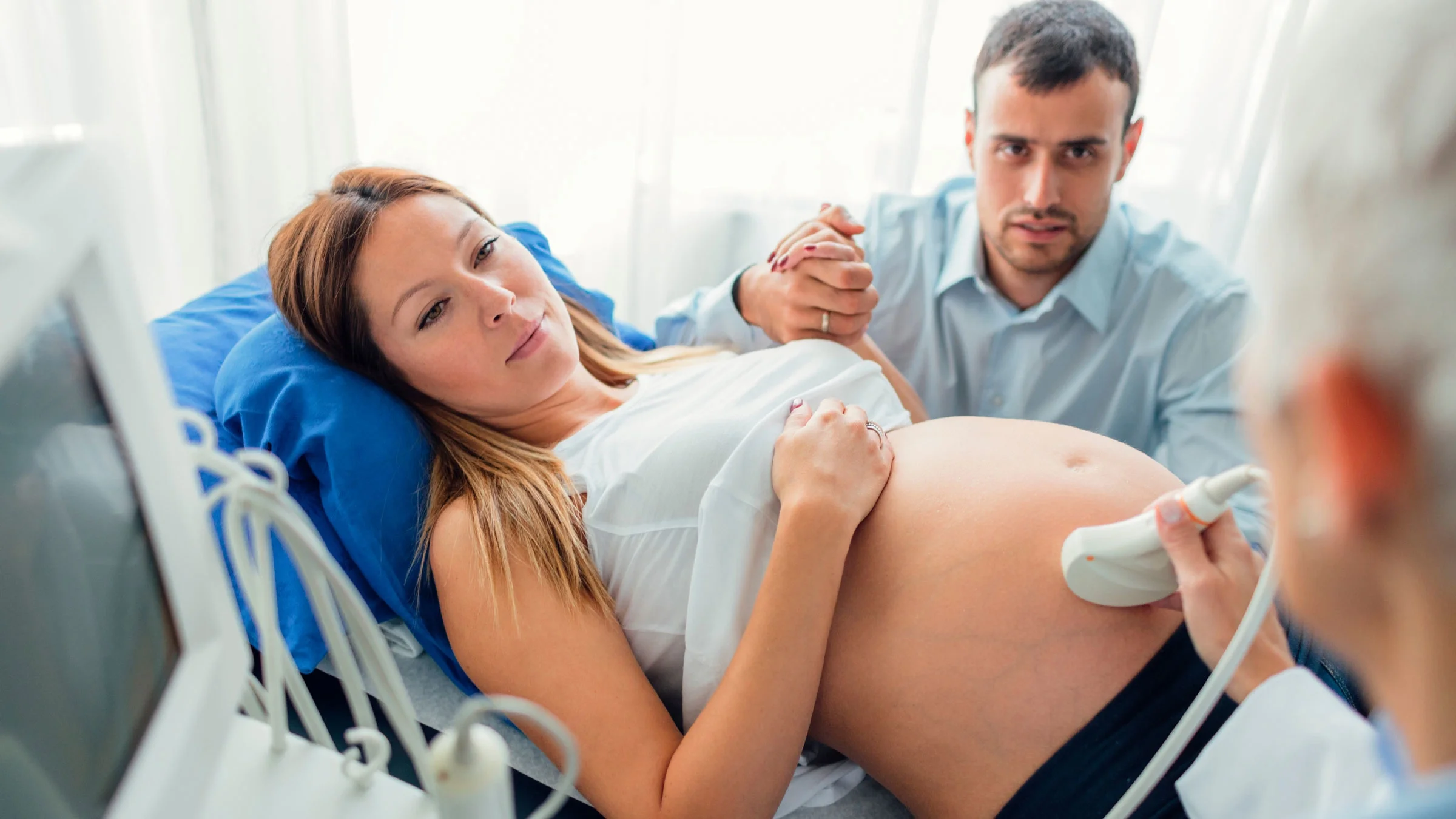A healthcare worker is doing a pregnancy ultrasound. 