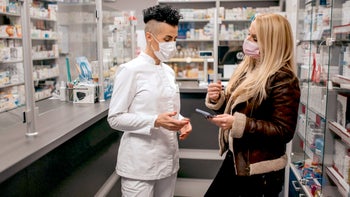 Pharmacies: customer showing phone to pharmacist 1290601847