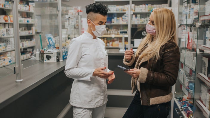 A customer showing their phone to a pharmacist.