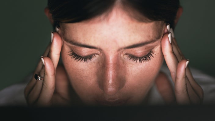 A close-up of someone holding their temples in pain.