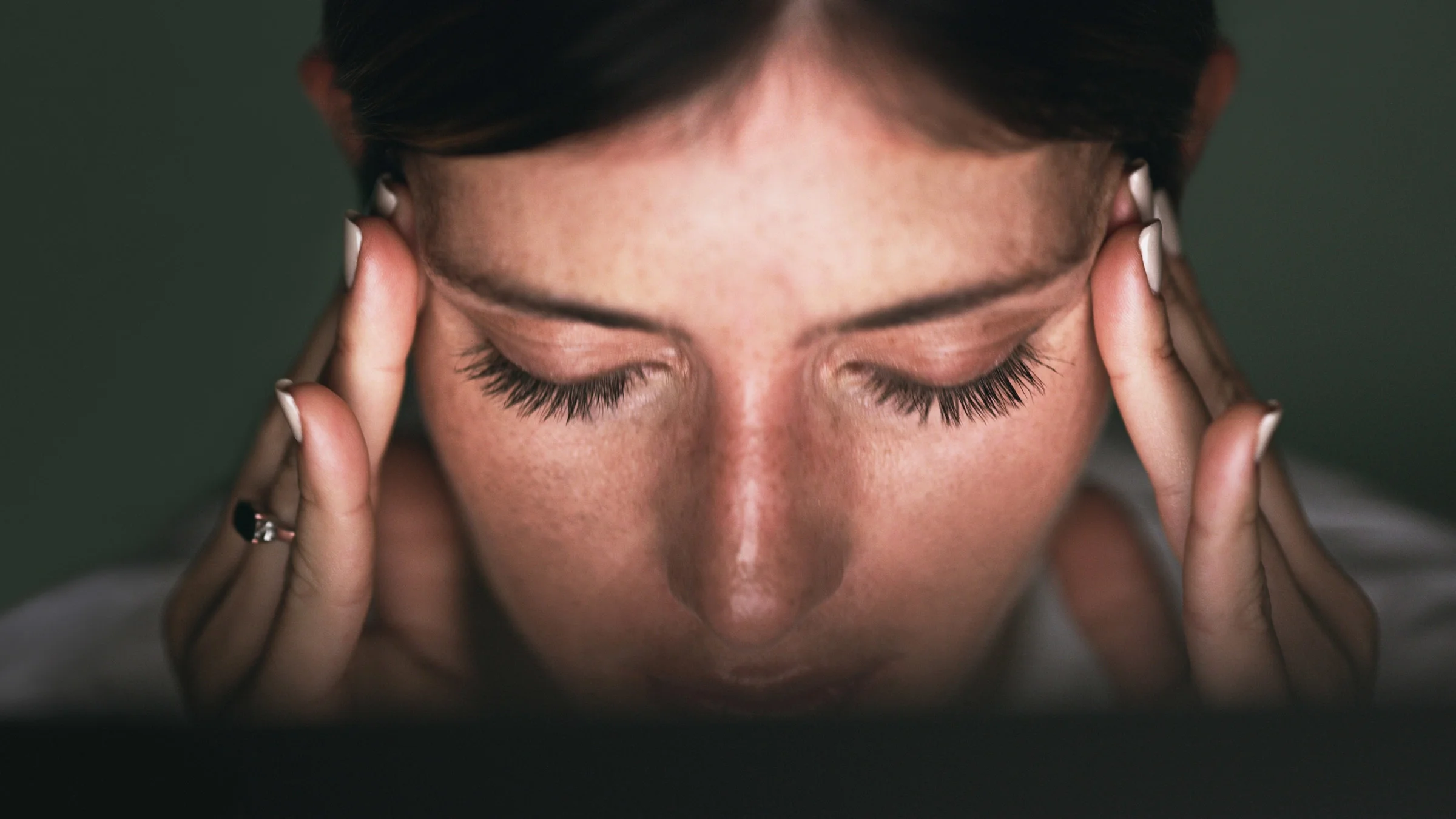 A close-up of someone holding their temples in pain.