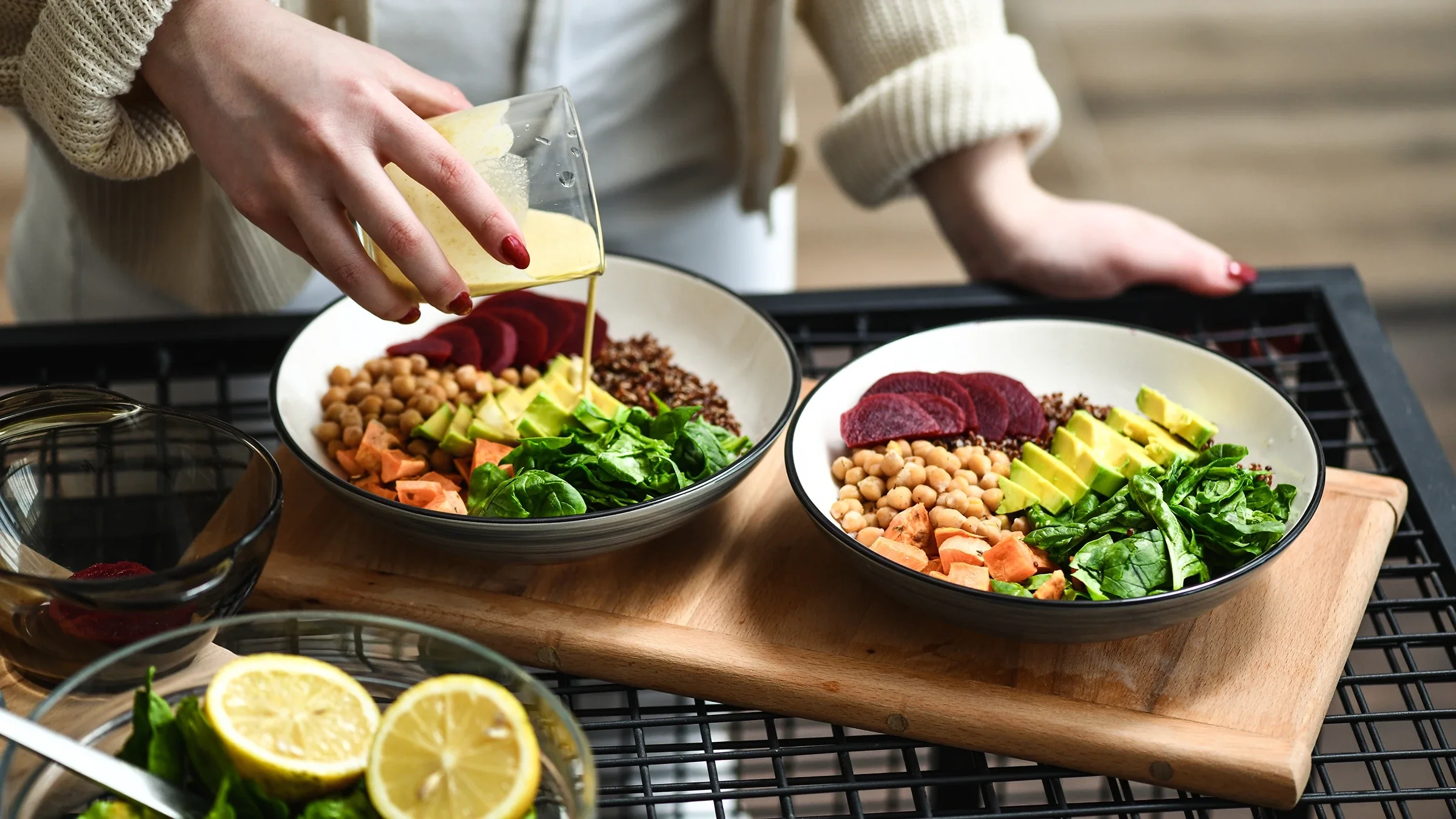 A woman pours dressing onto a plate of salad.