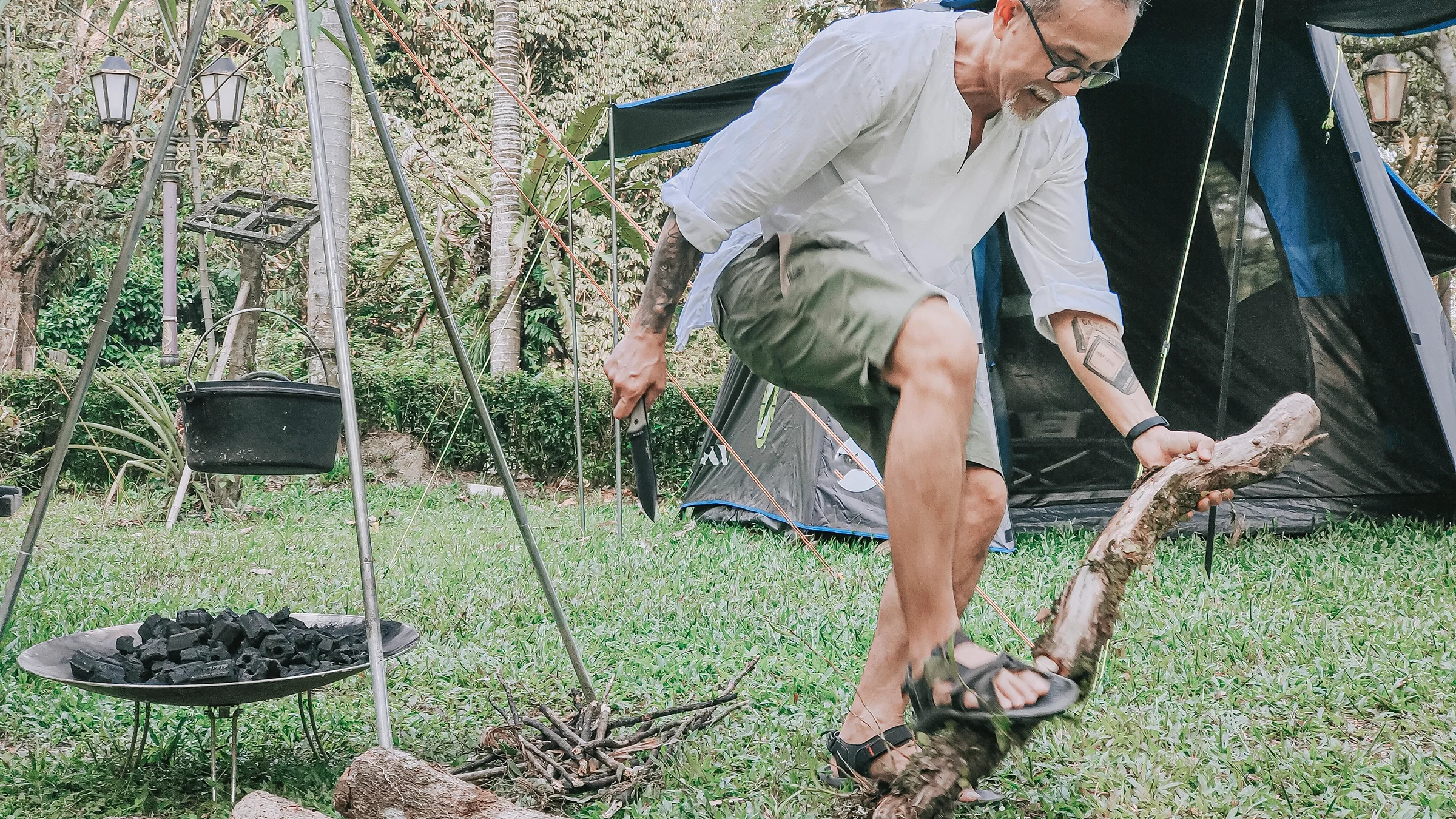 Man breaking down fire wood for campfire. You can see his tent in the background.
