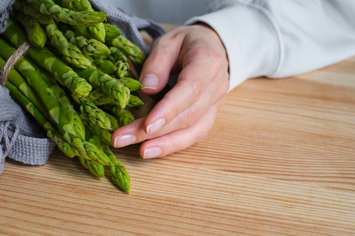 Close-up of a person unpacking their asparagus from their grocery bag.