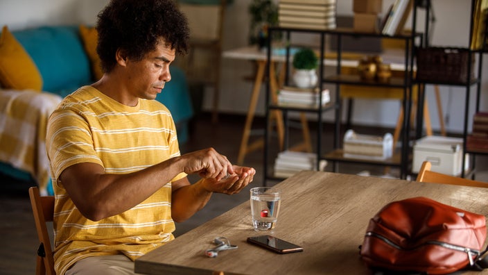 A man prepares to take his medication at home.