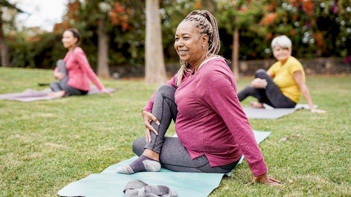 Senior women in the park practicing yoga together.