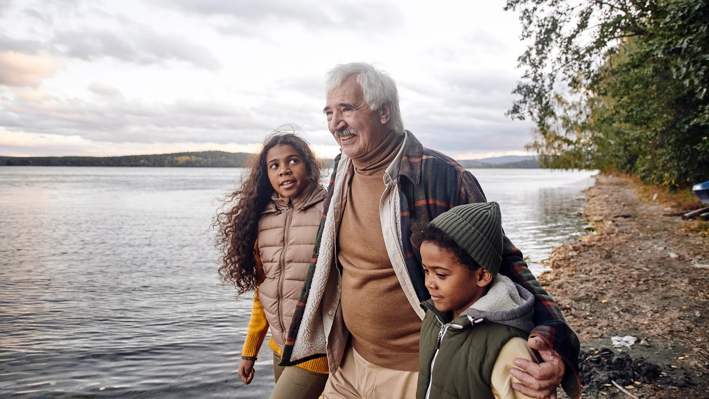 Grandfather walking with his two grandchildren by a lake.