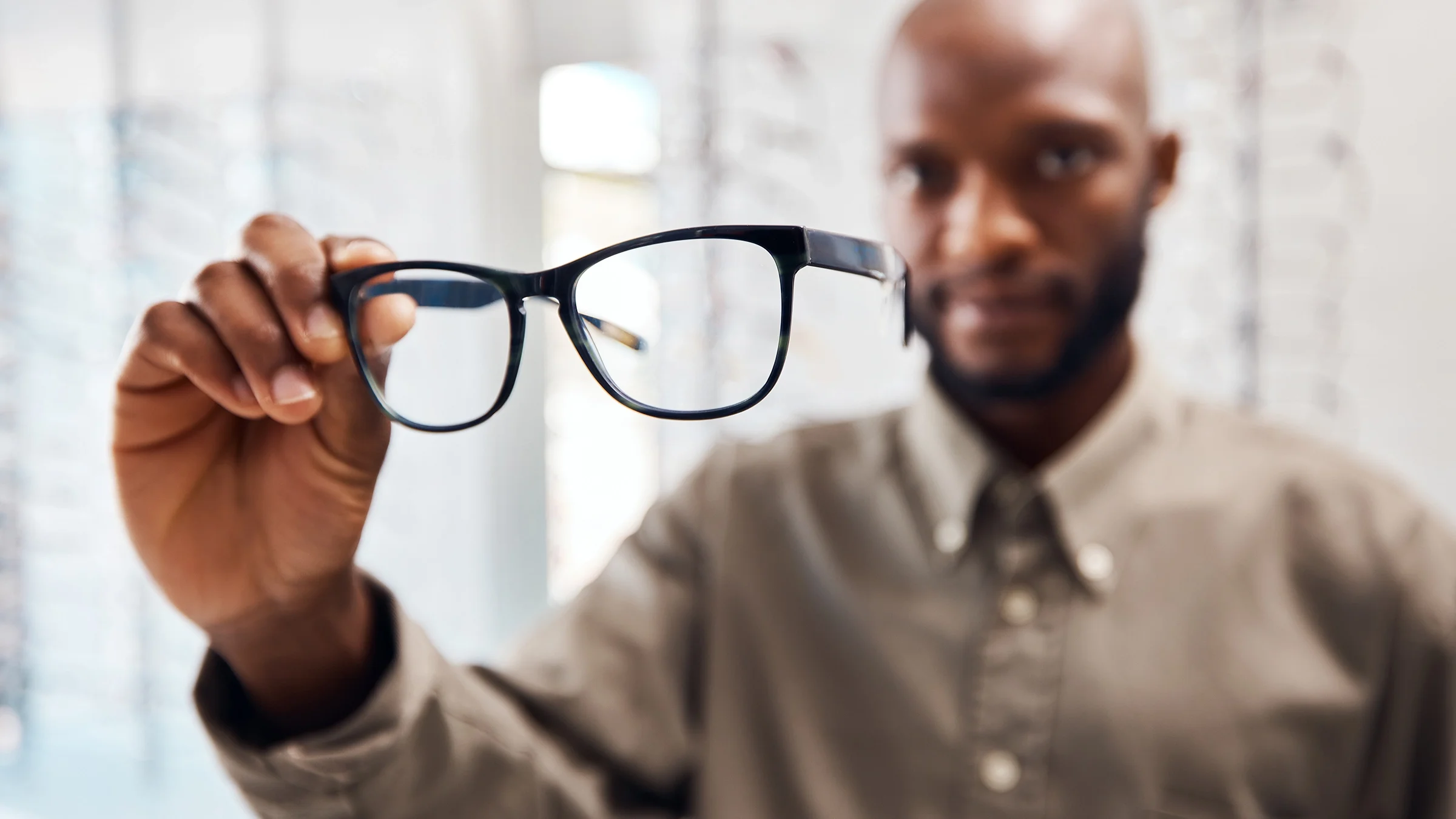 A man is holding a pair of glasses at an eyewear store.