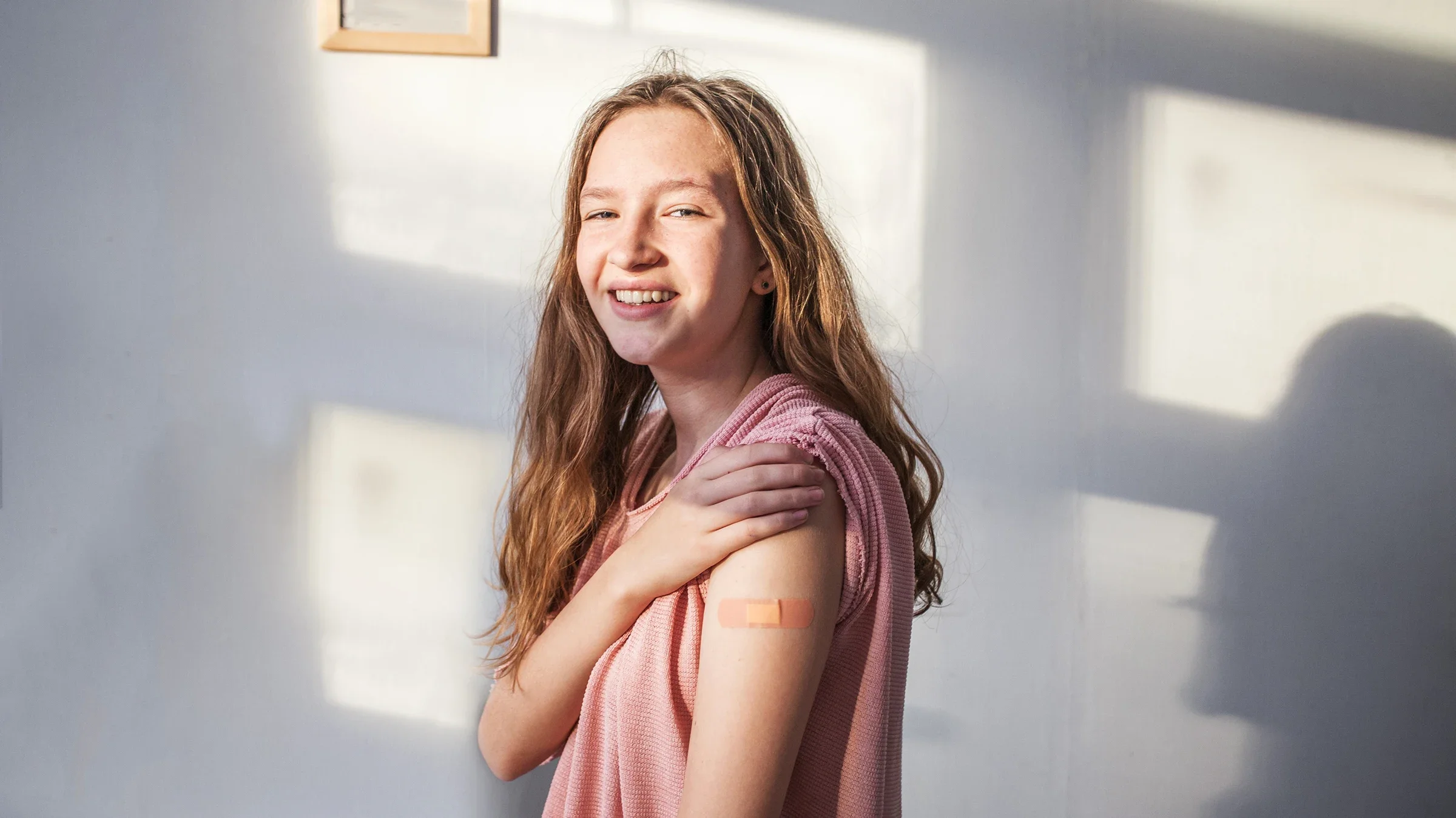 Young teenage girl showing off her bandage from a recent shot.
TatyanaGl/iStock via Getty Images