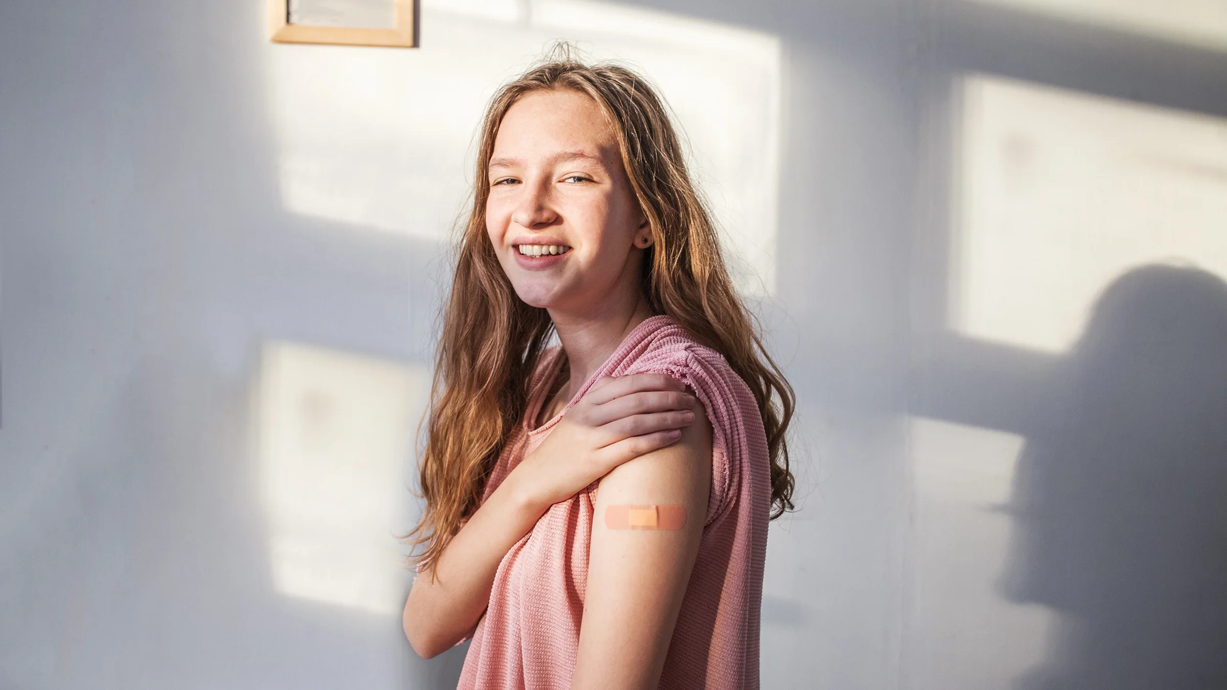 Young teenage girl showing off her bandage from a recent shot.