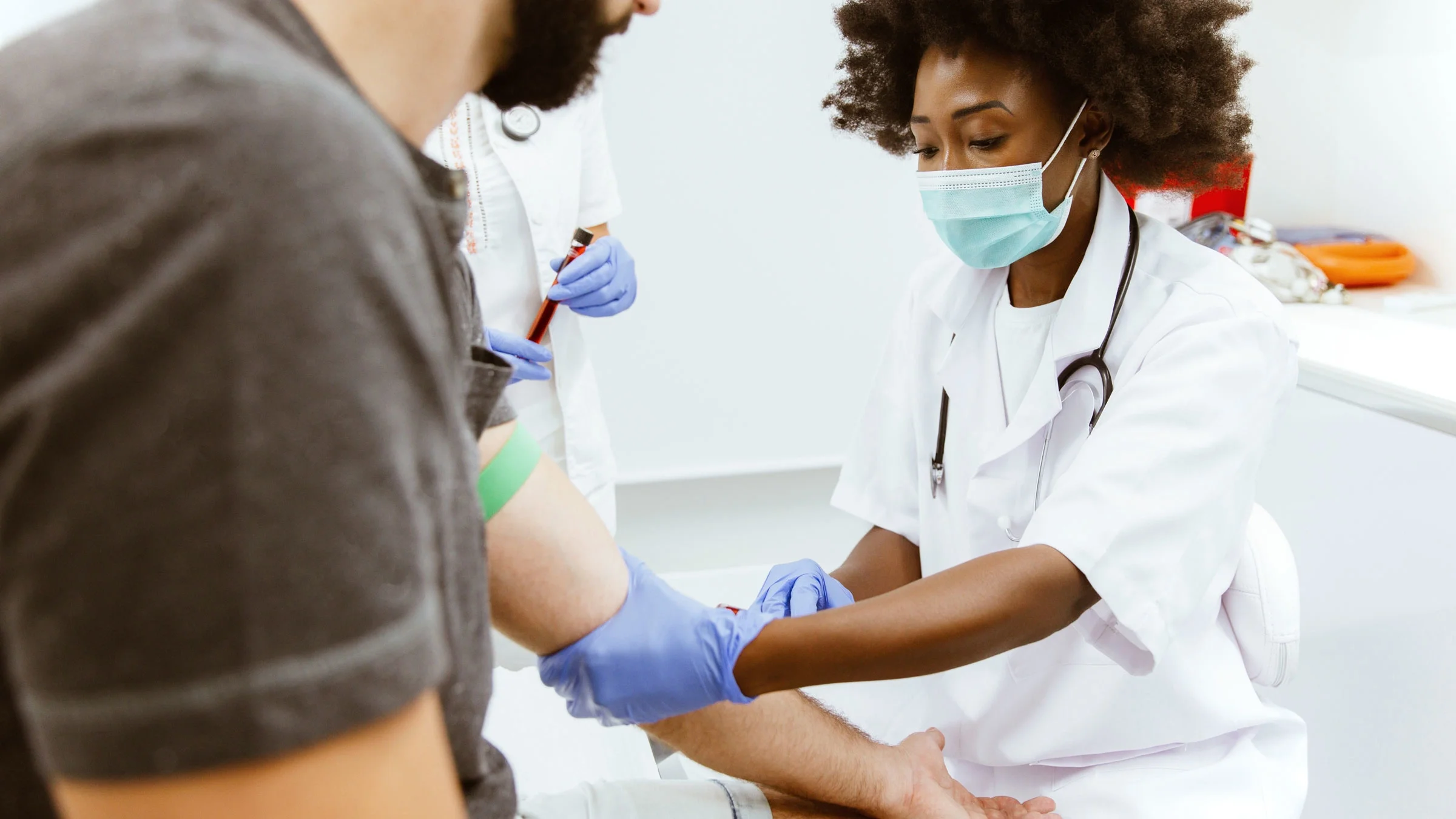 A healthcare provider is drawing blood from an arm.