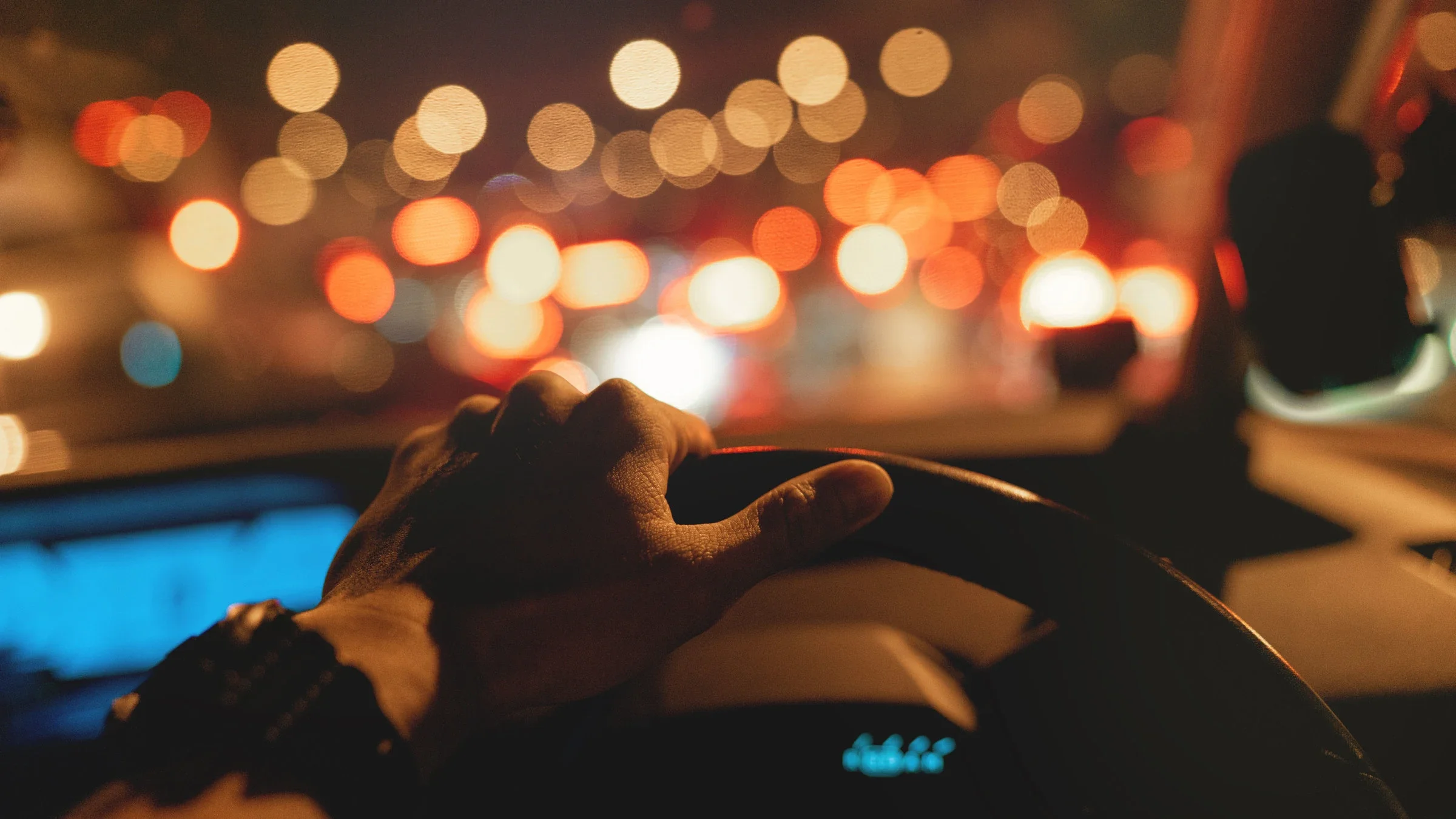 A close-up image shows a hand on a steering wheel at night.
Koh Sze Kiat/iStock via Getty Images
