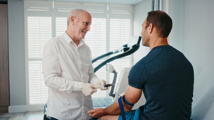 A doctor talking to a patient while conducting a blood test.