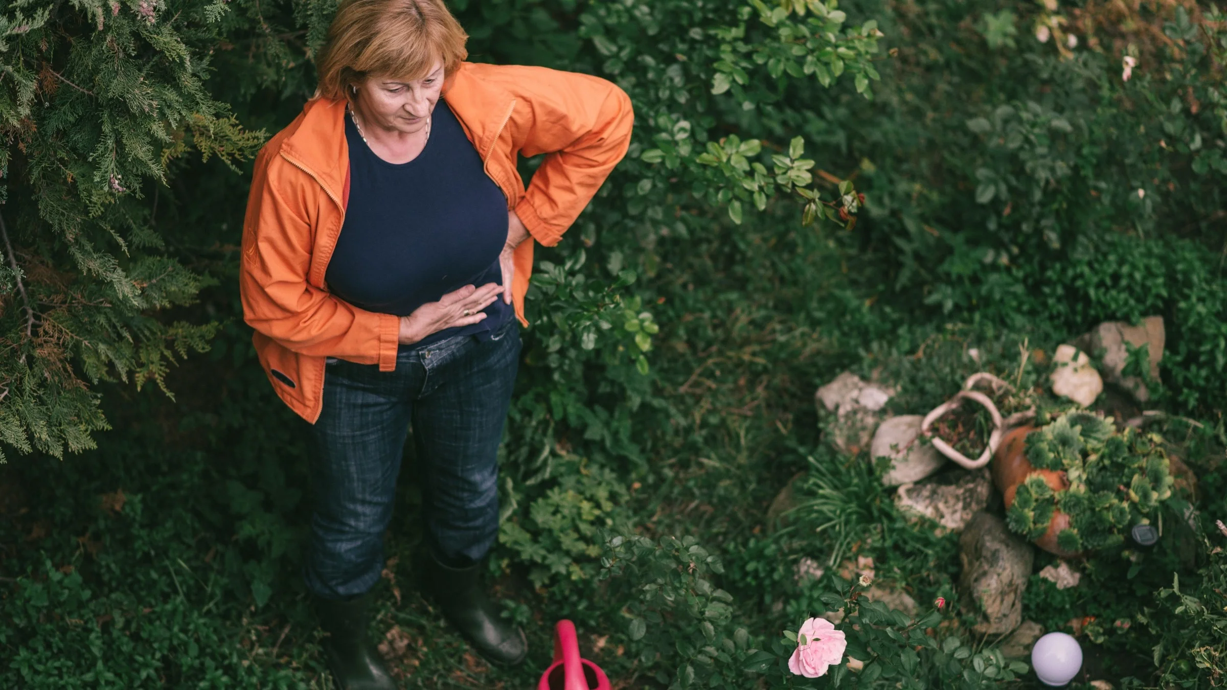 A person experiencing abdominal pain while gardening.