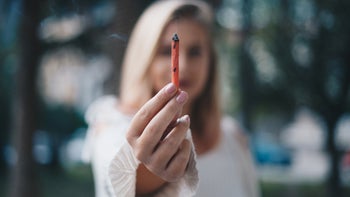 Health: Cannabis: woman holding marijuana joint to camera-924041670