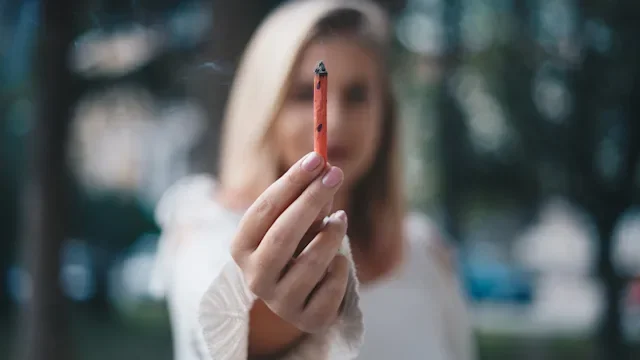 Health: Cannabis: woman holding marijuana joint to camera-924041670
