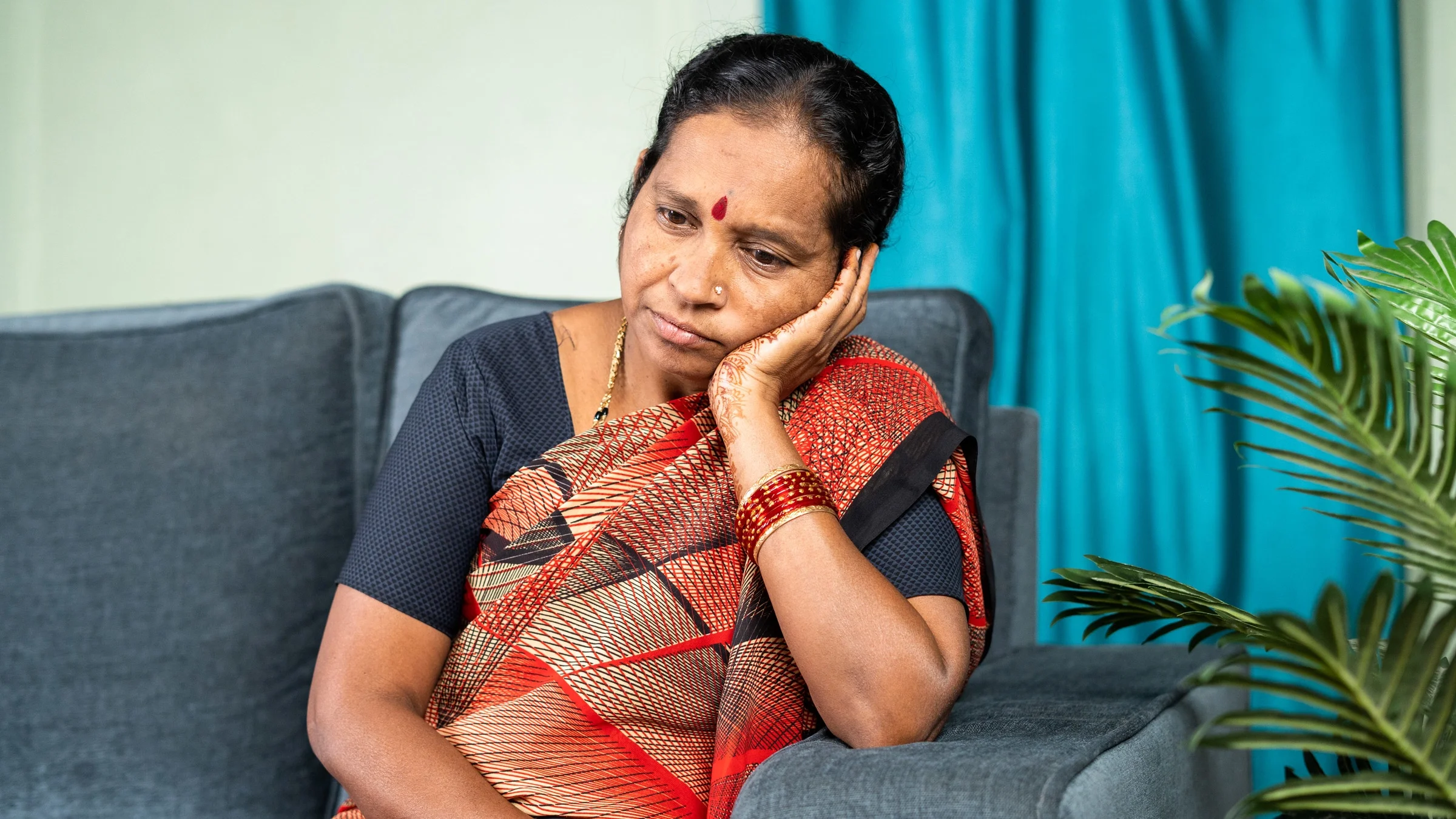 An older woman thinking of her couch, looking confused.