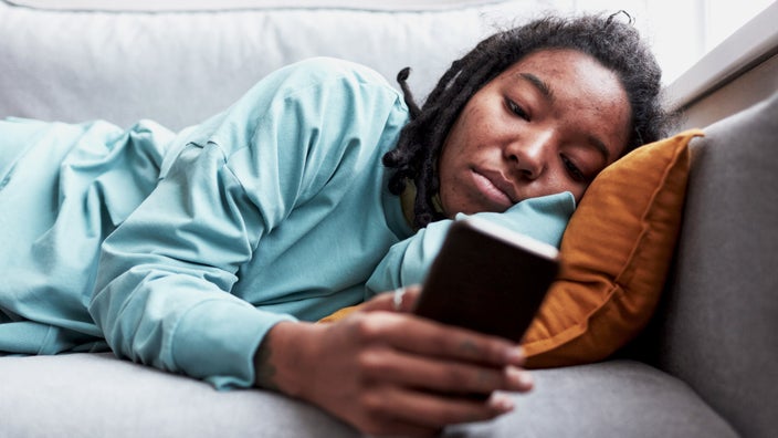 A person with acne looking something up on their phone.