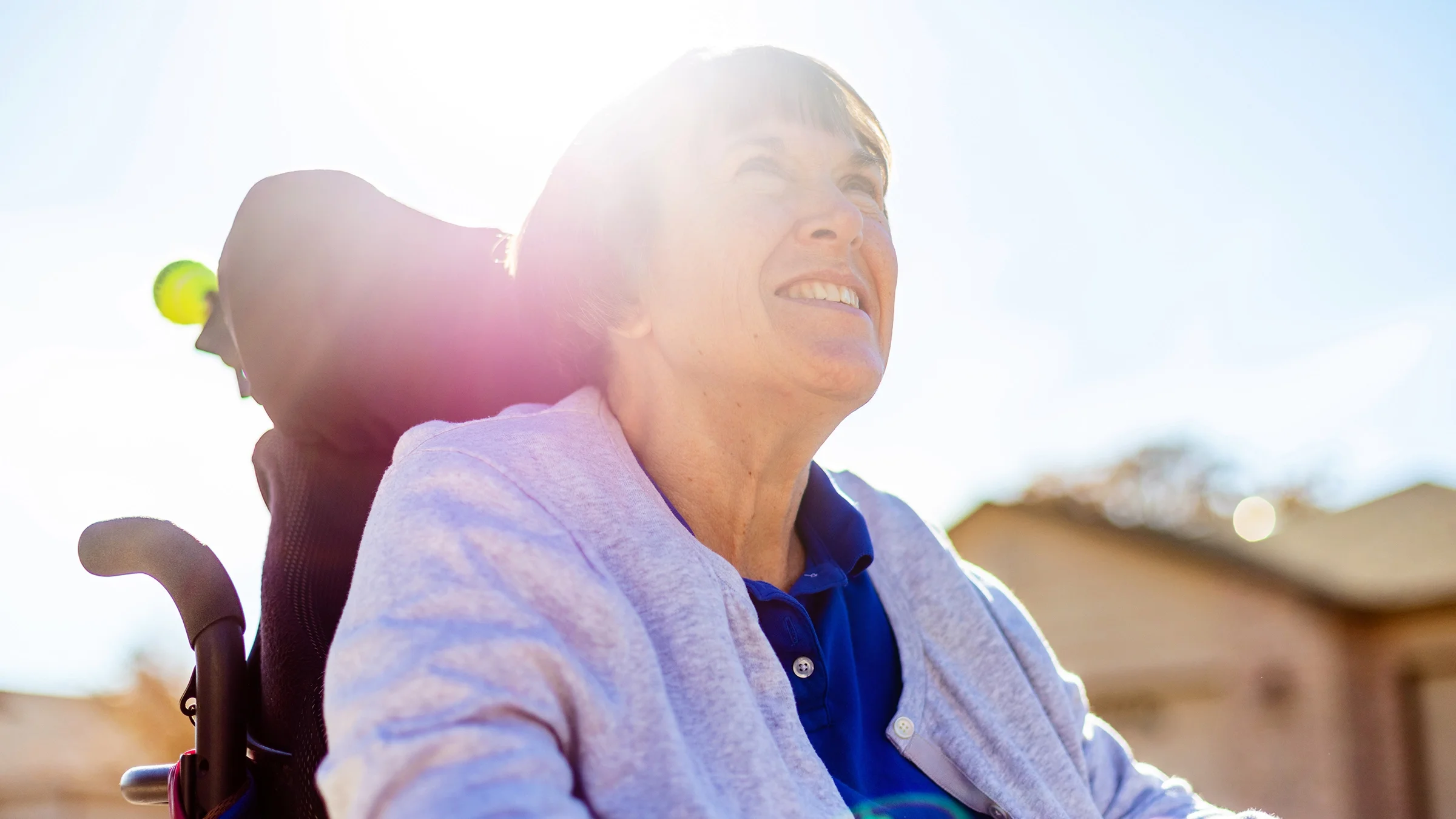 A woman in a wheelchair is looking up at the sky.
