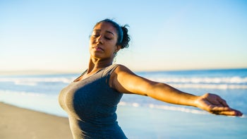 Health: health insurance: young-woman-practicing-yoga-on-beach-652383572
