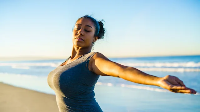 Health: health insurance: young-woman-practicing-yoga-on-beach-652383572