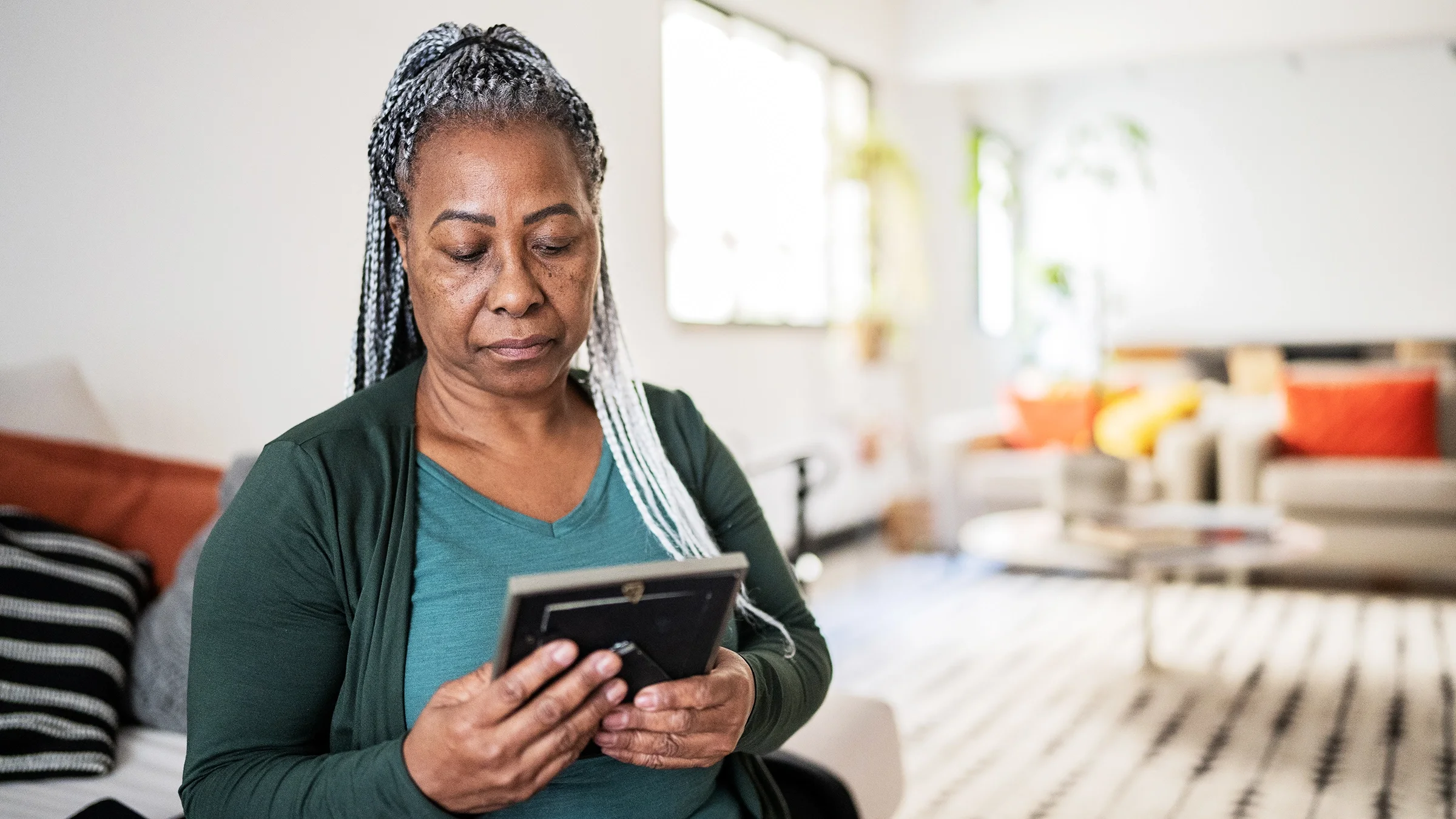 A woman holds and looks at a picture frame.