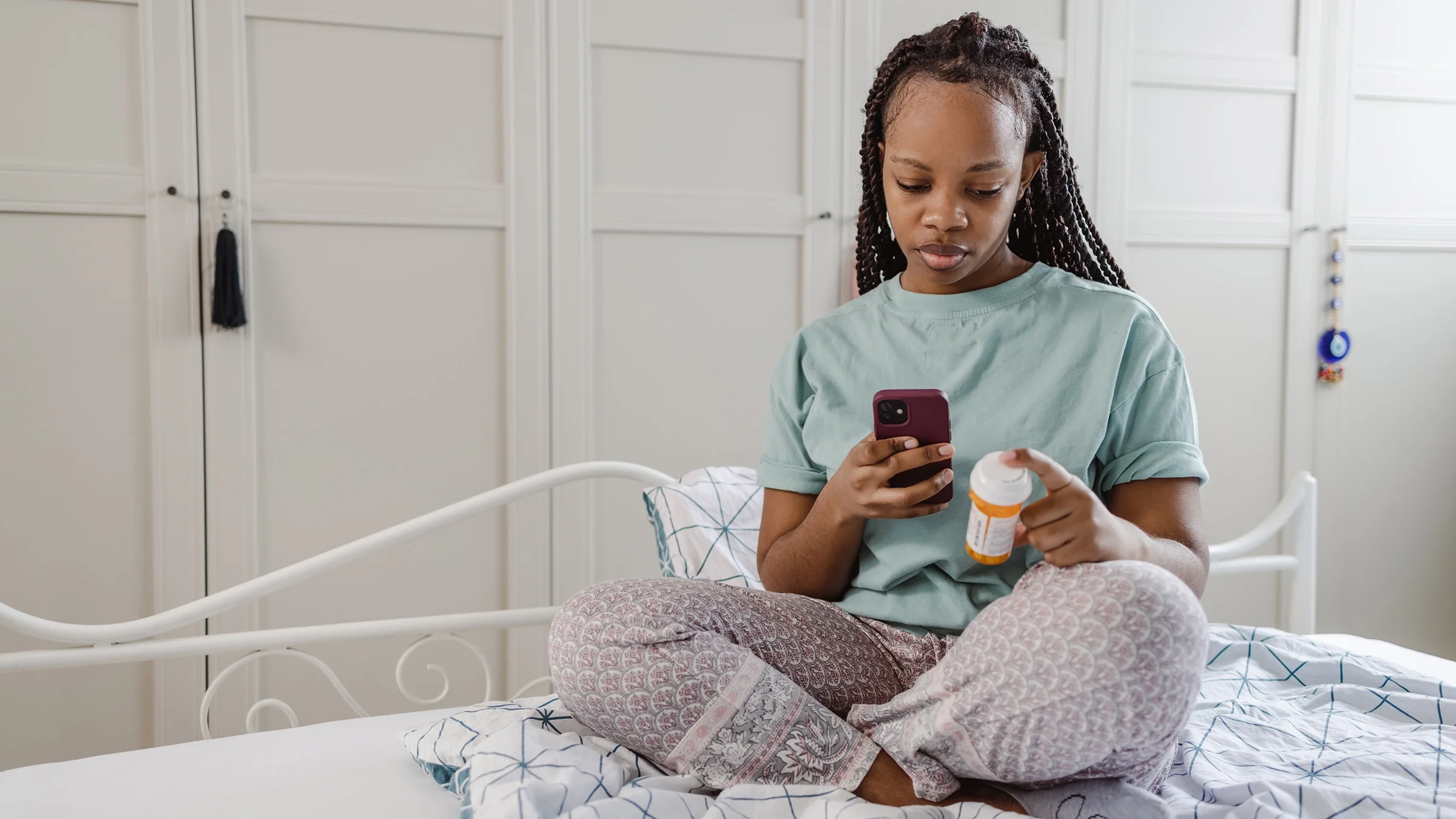 A woman sitting on the bed looks online for medicine side effects.