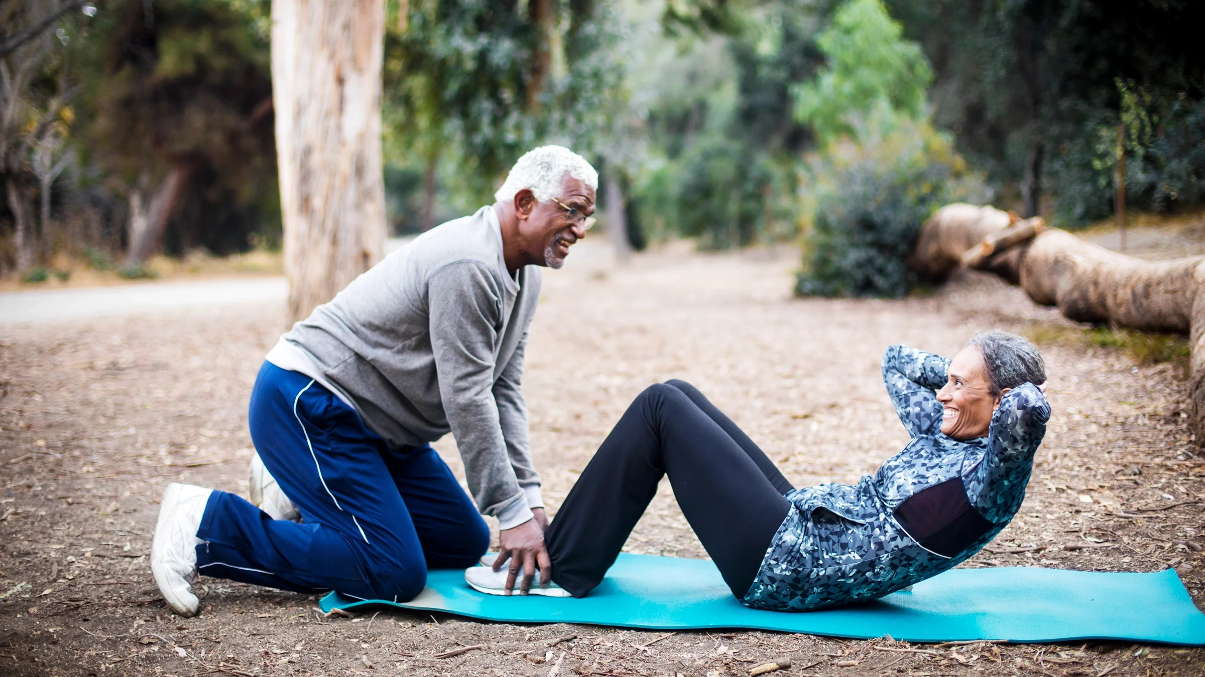 Man holds down woman's feet while doing sit-ups