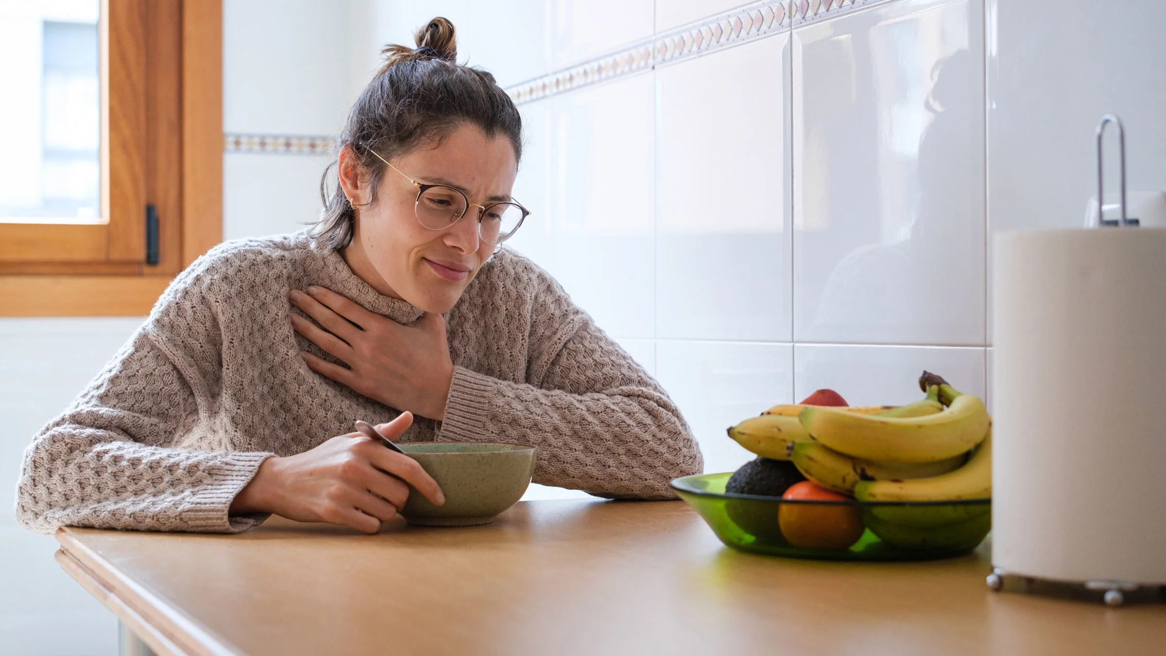 Woman with throat pain eating soup.